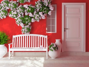 A red house with a white bench and floral decorations on the front porch.